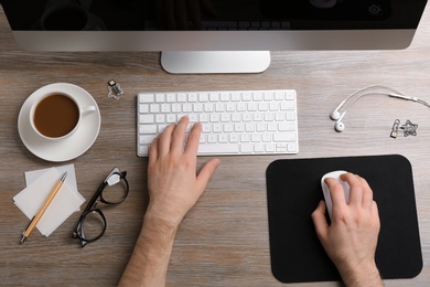 Photo of Man using computer mouse and keyboard at office table, top view