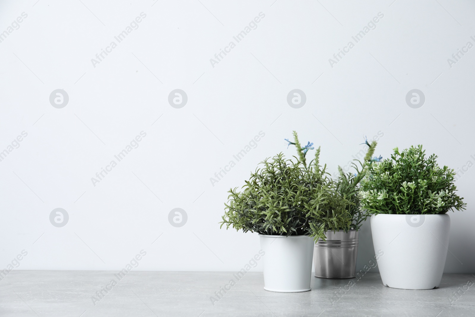 Photo of Different artificial potted herbs on light grey table, space for text