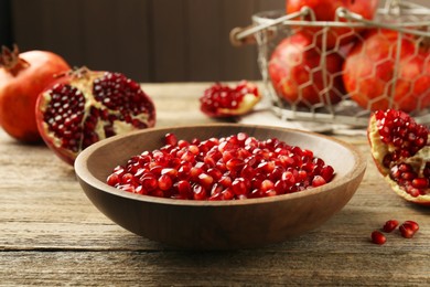 Ripe juicy pomegranate grains in bowl on wooden table