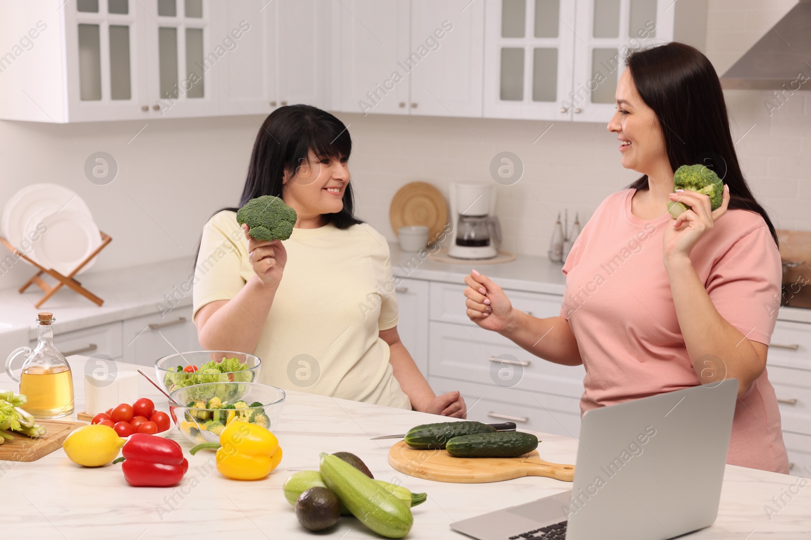 Photo of Happy overweight women having fun while cooking together in kitchen