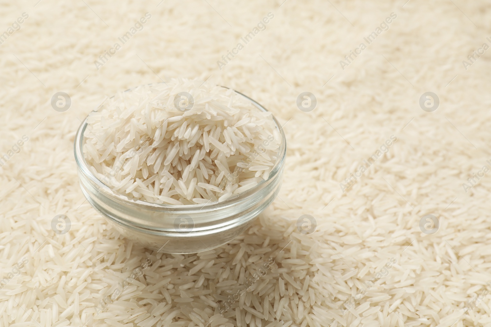 Photo of Bowl on raw basmati rice, closeup view. Space for text