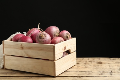 Photo of Crate with red turnips on wooden table. Space for text