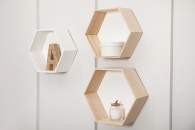 Honeycomb shaped shelves with decorative elements on white wall