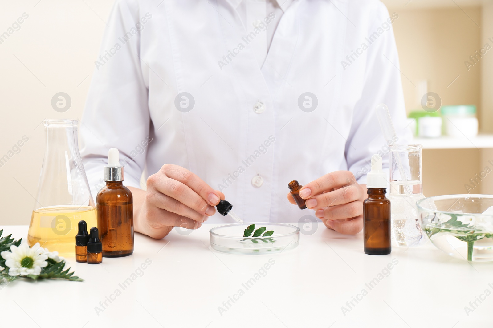 Photo of Female dermatologist creating skin care product at table, closeup