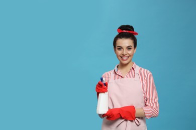 Photo of Young housewife with detergent on light blue background, space for text