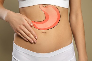 Woman with image of healthy stomach on beige background, closeup