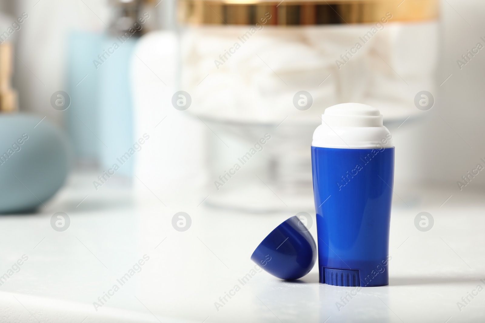 Photo of Stick deodorant with toiletry on table in bathroom, , space for text