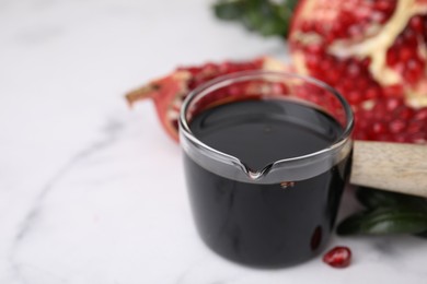 Photo of Tasty pomegranate sauce on white table, closeup. Space for text