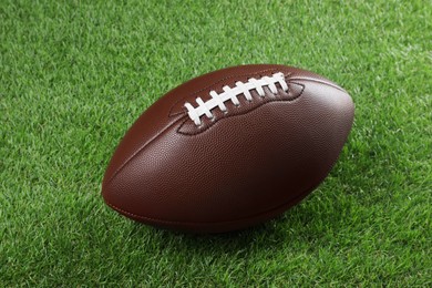 Brown leather American football ball on green grass