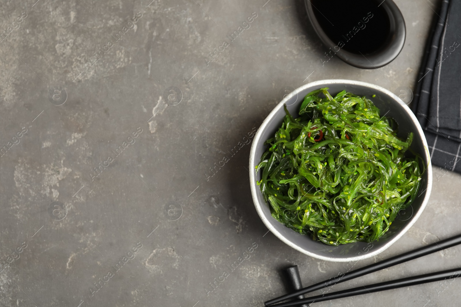 Photo of Japanese seaweed salad served on grey table, flat lay. Space for text