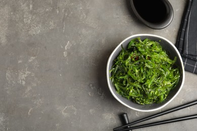 Photo of Japanese seaweed salad served on grey table, flat lay. Space for text