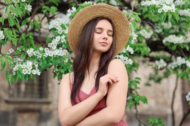 Photo of Beautiful woman in straw hat near blossoming tree on spring day