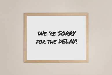 Image of Frame with phrase We're Sorry For The Delay on beige wall
