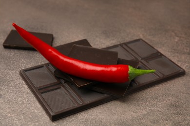 Delicious chocolate and fresh red chili pepper on grey textured table
