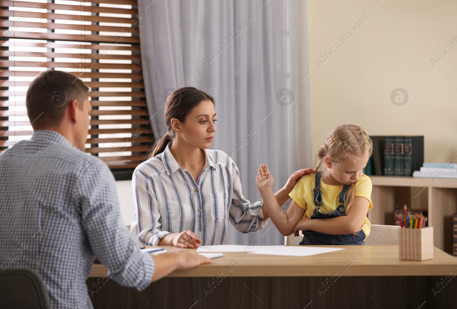 Photo of Child psychotherapist working with little girl and her mother in office