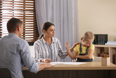 Child psychotherapist working with little girl and her mother in office
