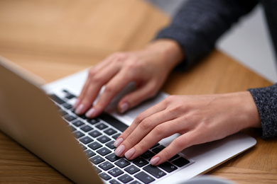Photo of Woman working on modern laptop at table, closeup