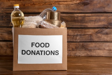 Photo of Donation box with food on wooden background