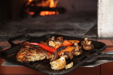 Photo of Taking grill pan with meat and garnish out of oven