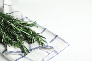 Photo of Fresh green rosemary and napkin on white table. Space for text