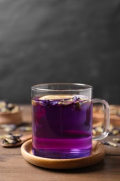 Photo of Glass mug of organic blue Anchan on wooden table, space for text. Herbal tea