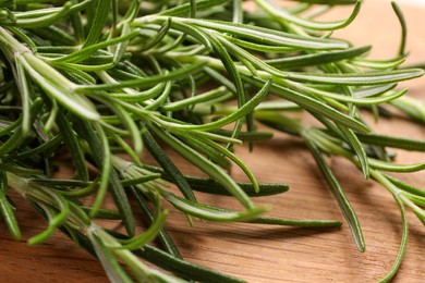 Photo of Sprigs of fresh rosemary on wooden board, closeup