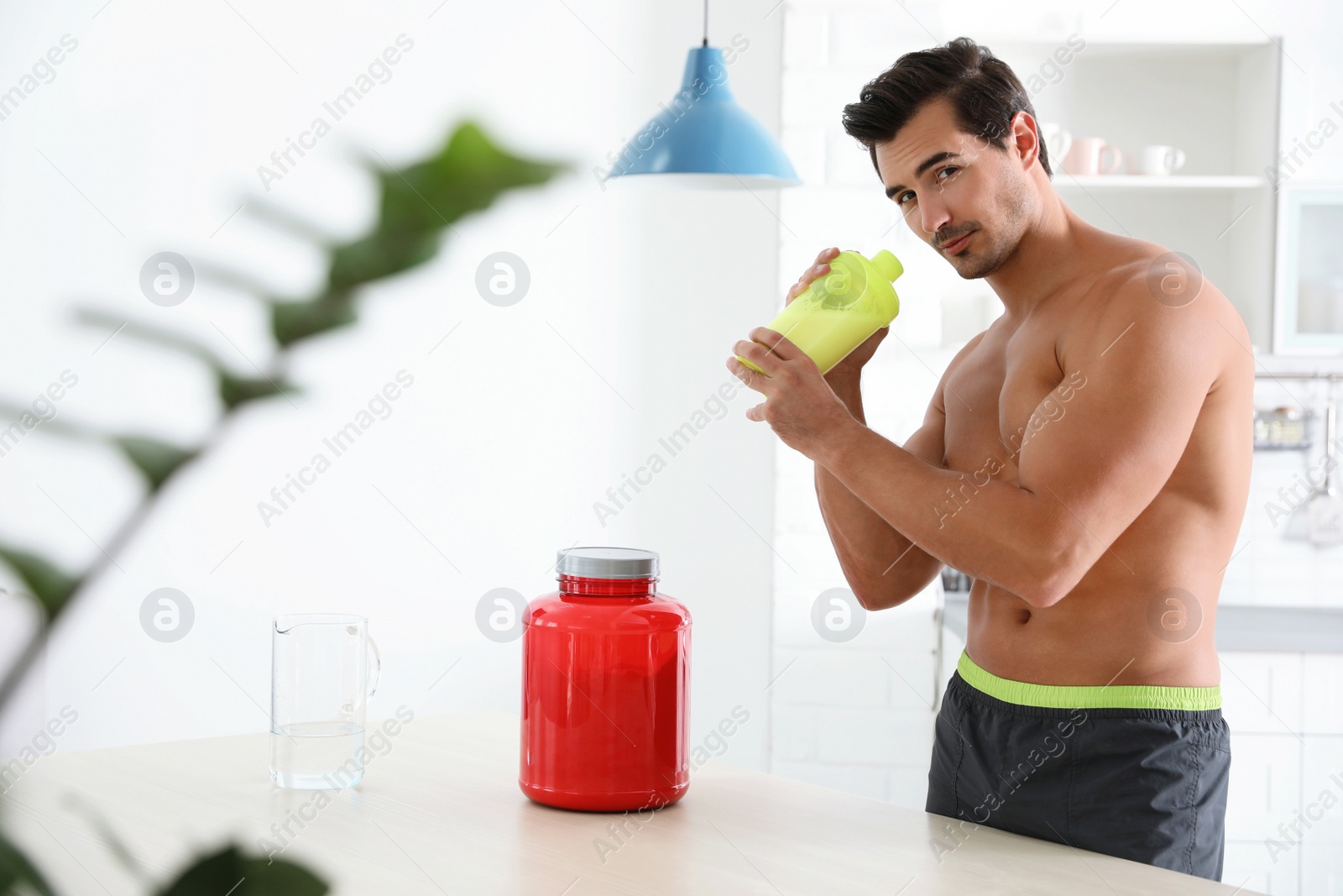 Photo of Young shirtless athletic man with protein shake powder in kitchen, space for text