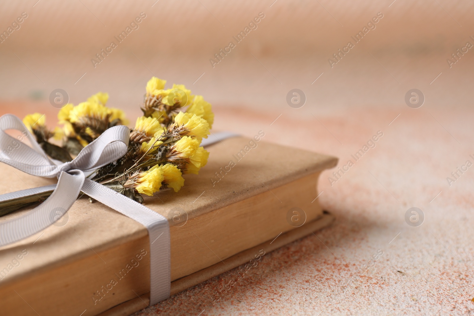 Photo of Book decorated with flowers on beige textured table, closeup