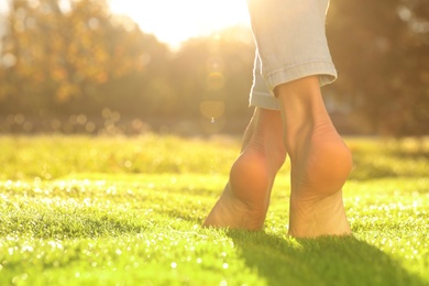 Young woman walking barefoot on fresh green grass, closeup