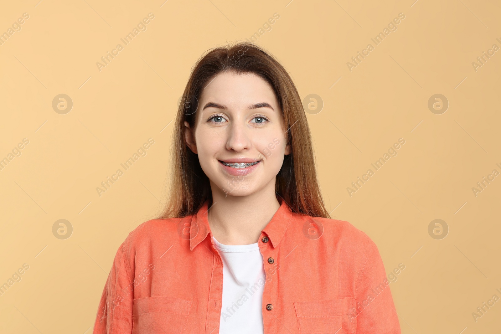 Photo of Portrait of smiling woman with dental braces on beige background