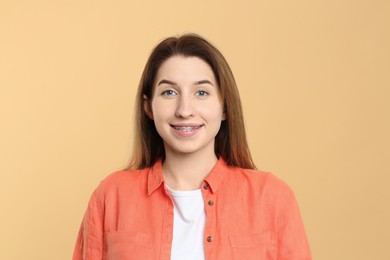 Photo of Portrait of smiling woman with dental braces on beige background