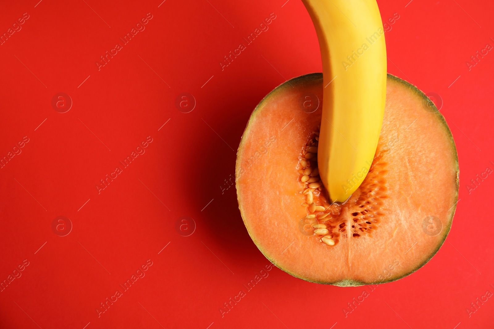 Photo of Flat lay composition with fresh banana and melon on red background, space for text. Sex concept