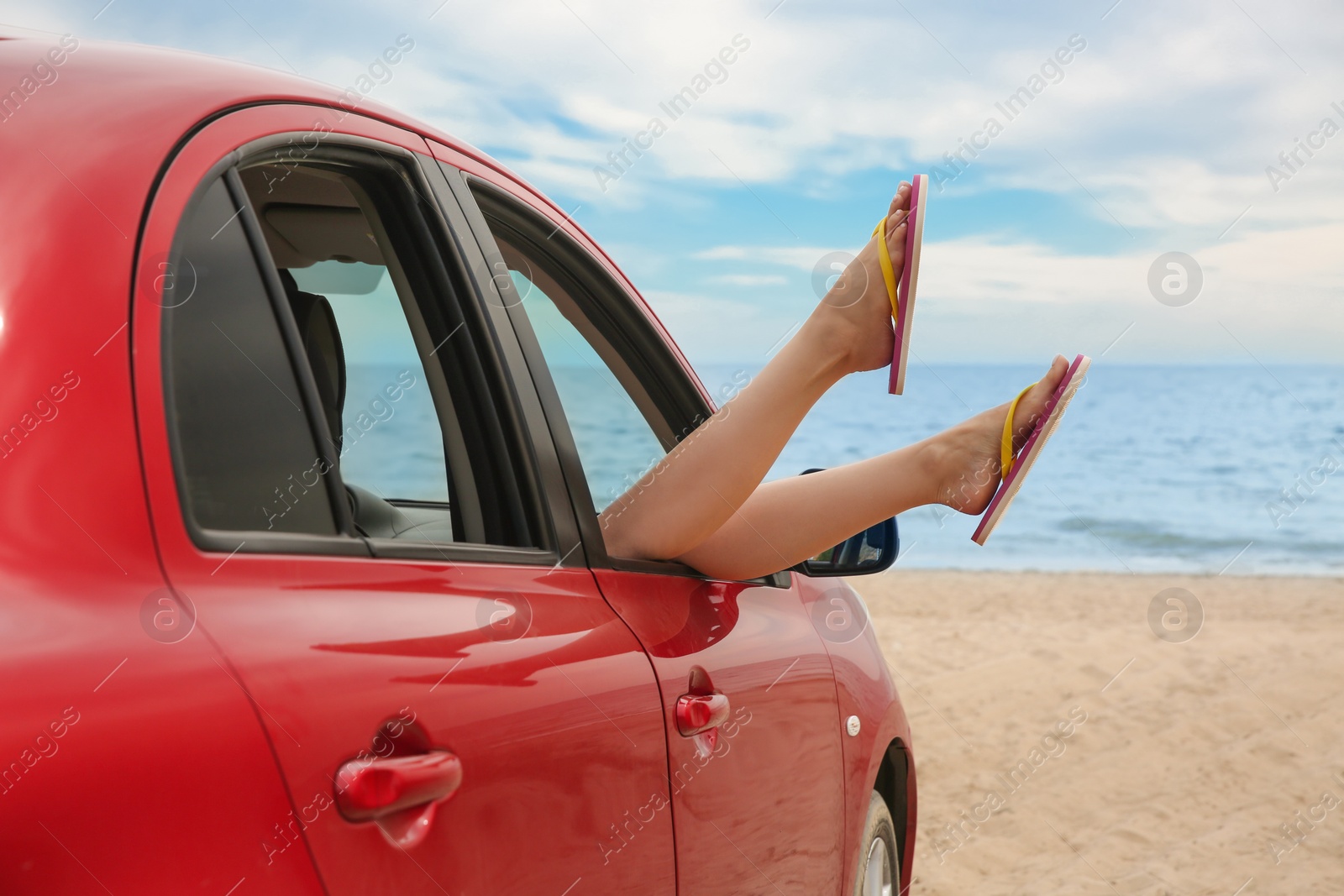 Photo of Woman showing legs from car, closeup. Summer vacation trip