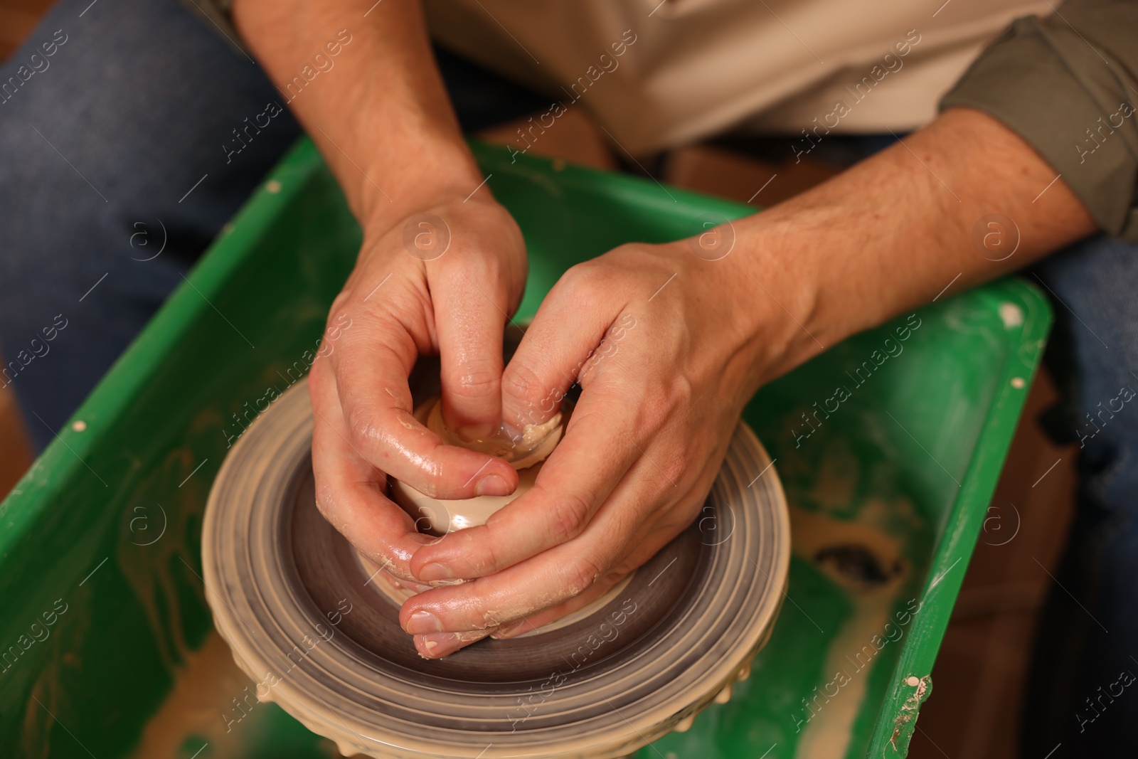 Photo of Clay crafting. Man making bowl on potter's wheel, closeup