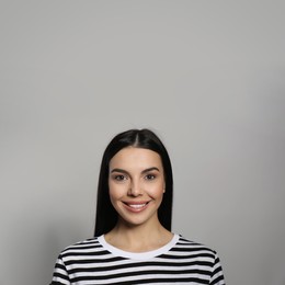 Photo of Portrait of happy young woman with beautiful black hair and charming smile on light grey background