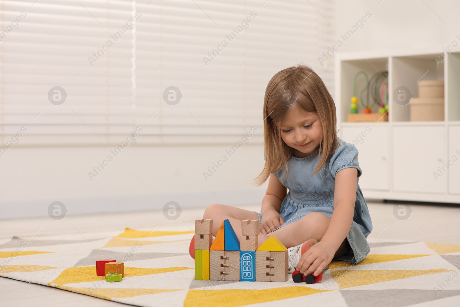 Photo of Cute little girl playing with wooden toys indoors, space for text