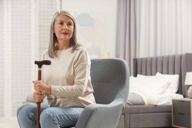 Photo of Mature woman with walking cane in armchair at home