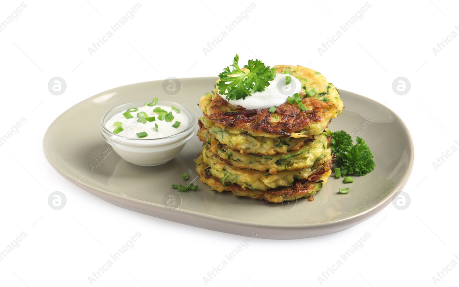 Photo of Delicious zucchini fritters with sour cream on white background