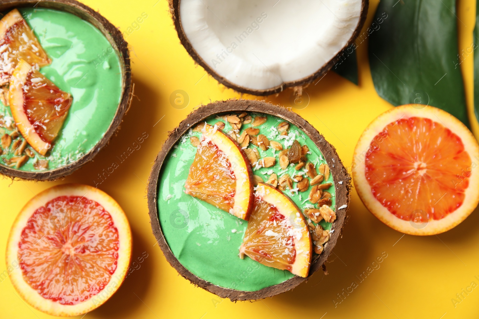 Photo of Coconut shells with yummy spirulina smoothie on color background, top view