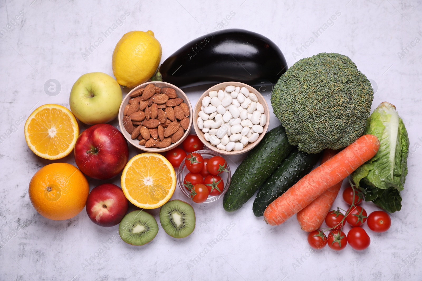 Photo of Almonds, beans, fresh fruits and vegetables on light grey textured background, flat lay. Low glycemic index diet