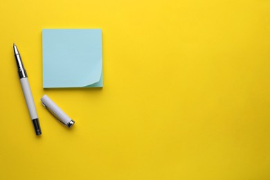 Photo of Paper note and pen on yellow background, flat lay. Space for text