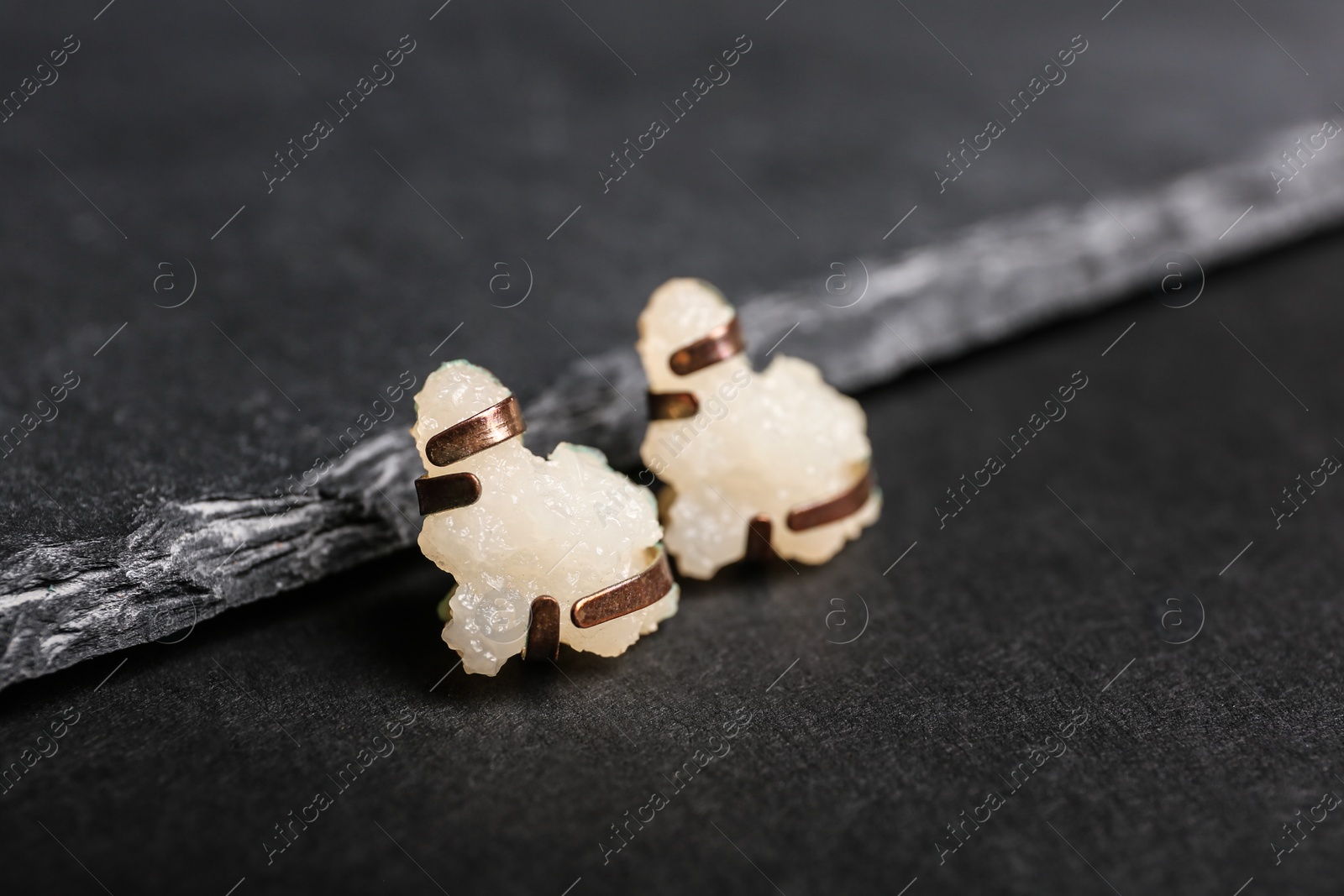 Photo of Stylish studs on black background, space for text. Luxury jewelry