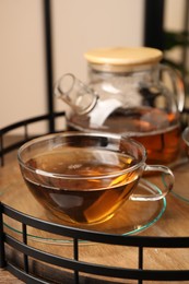 Photo of Aromatic tea in glass cups and teapot on table, closeup