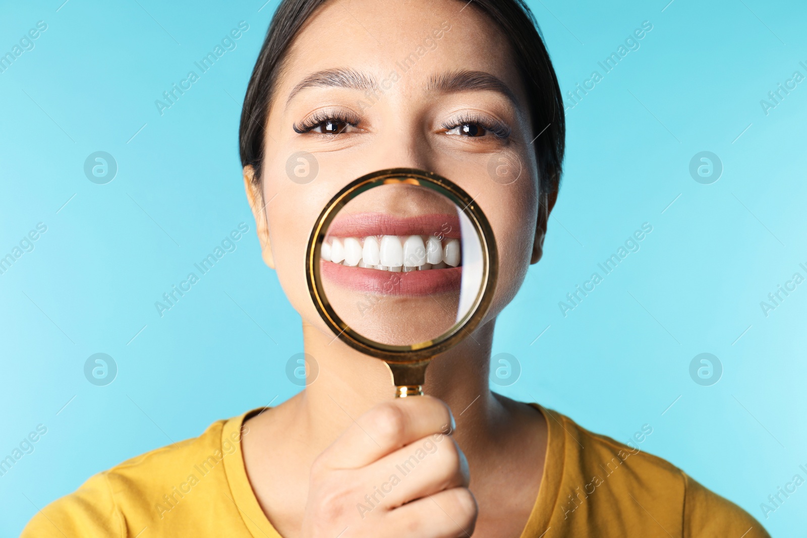 Photo of Young woman with healthy teeth and magnifier on color background, closeup