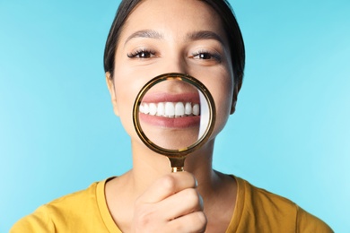 Photo of Young woman with healthy teeth and magnifier on color background, closeup