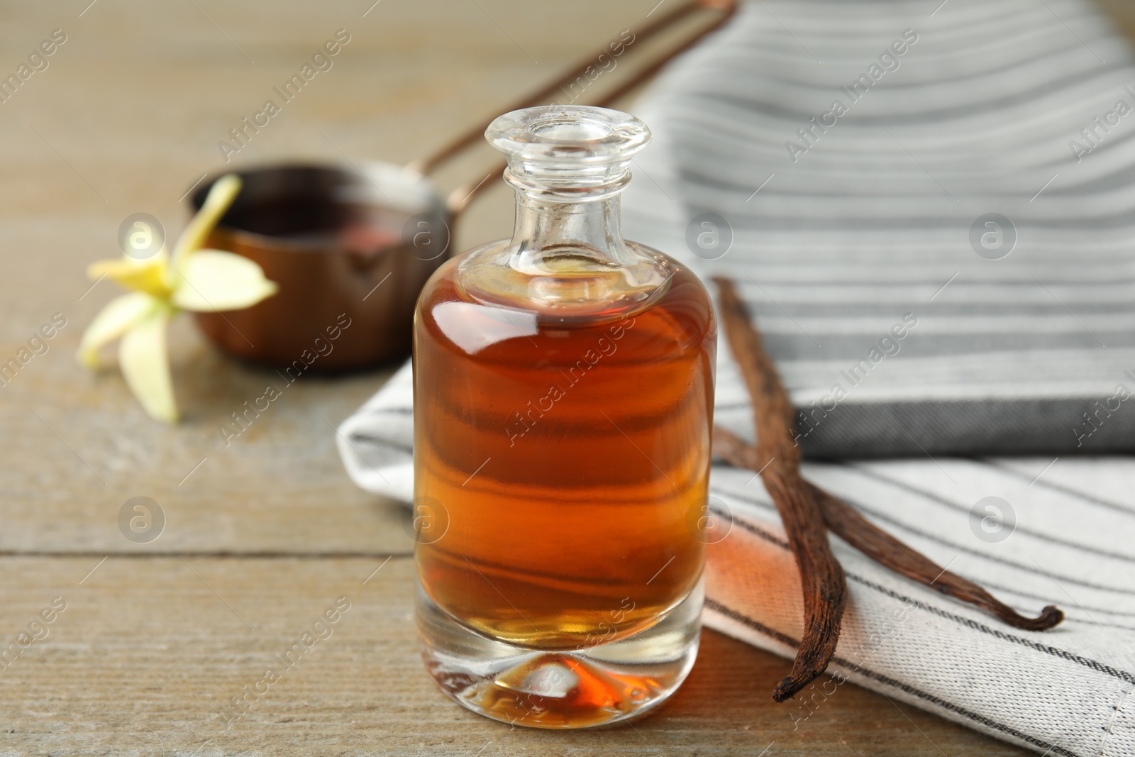 Photo of Aromatic homemade vanilla extract on wooden table, closeup