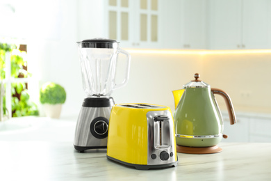 Photo of Set of modern home appliances on white marble table in kitchen