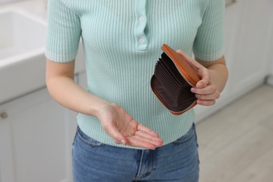 Woman with empty wallet at home, closeup