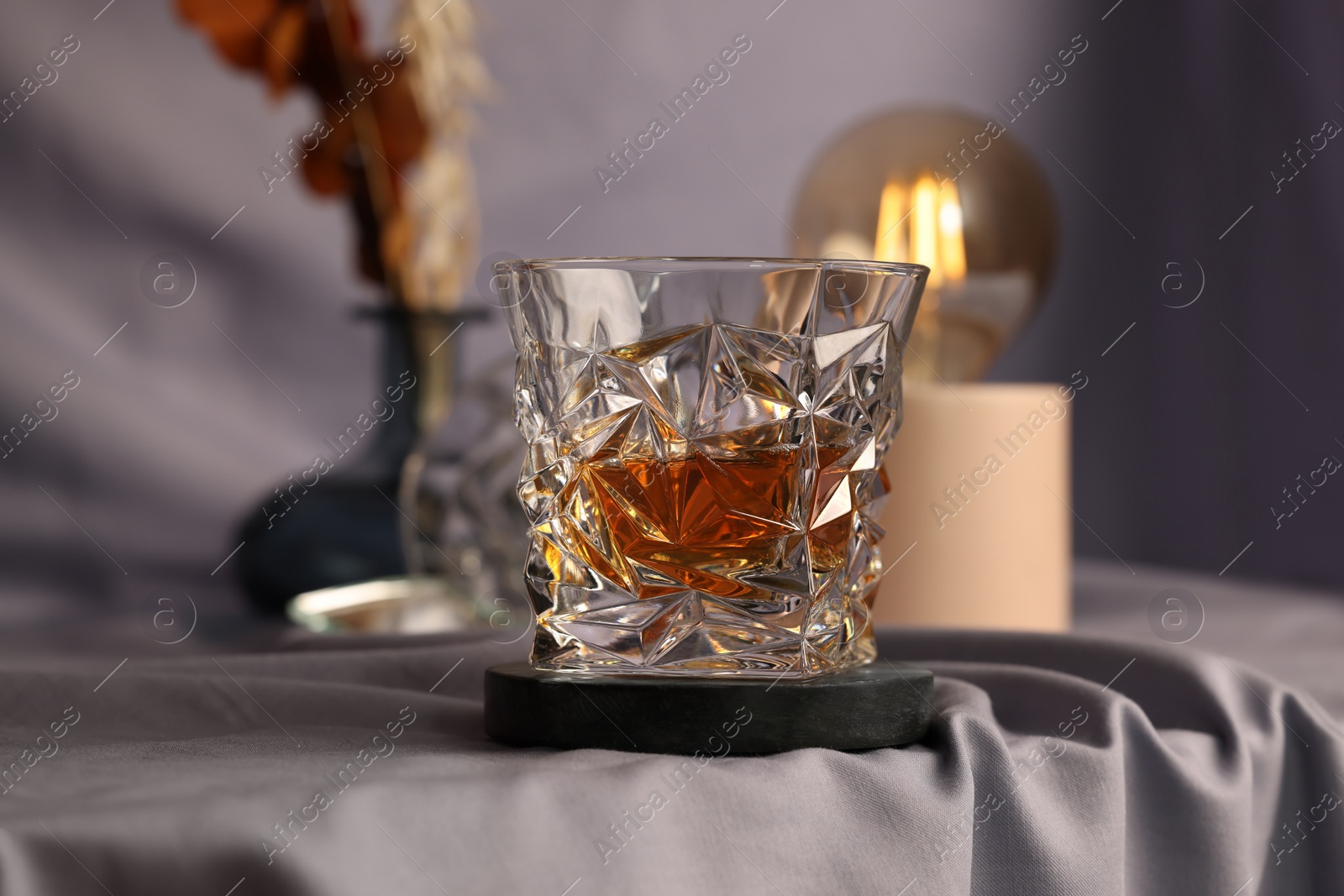 Photo of Glass of tasty alcohol drink on grey fabric