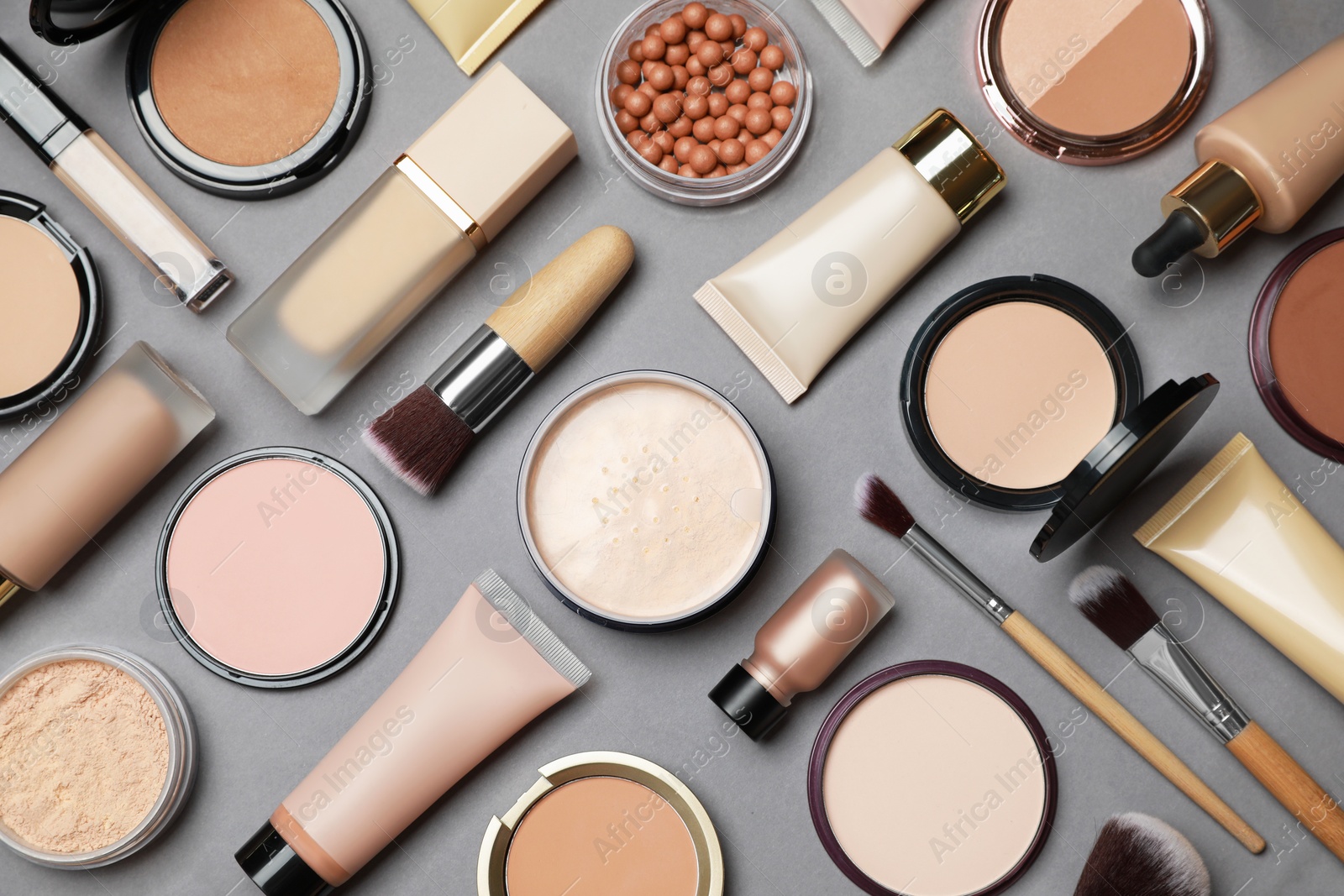 Photo of Face powders and other makeup products on grey background, flat lay